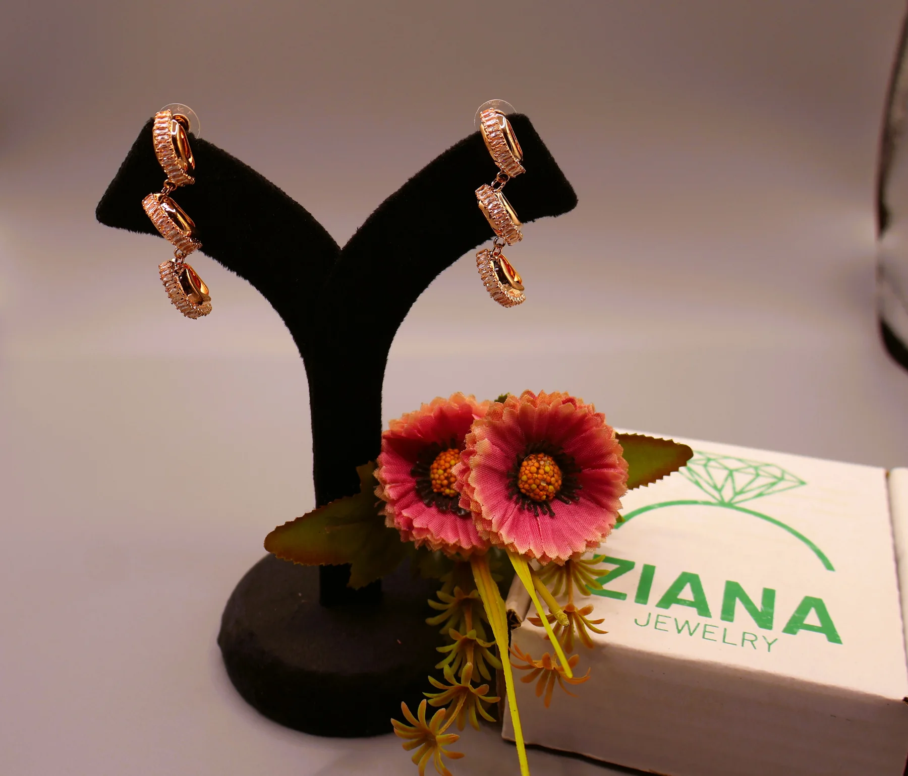 Rose-gold-tone baguette crystal link earrings on a display stand