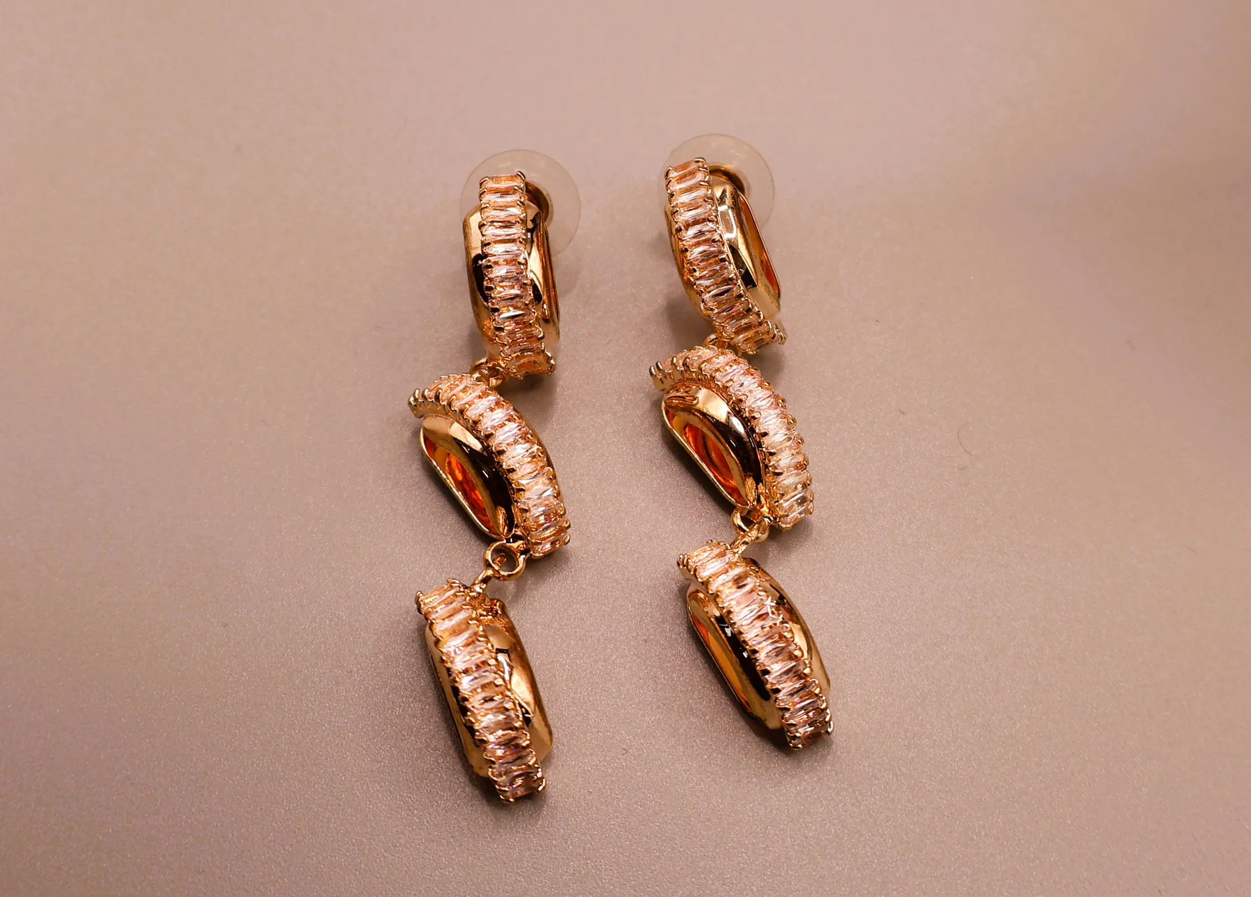 Close-up of rose-gold-tone triple-link crystal drop earrings